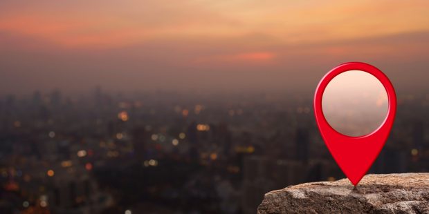 Red location icon on a rock overlooking a act at sunfall