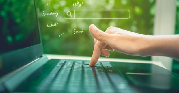 Laptop in a garden background with a hand and the words how when why.