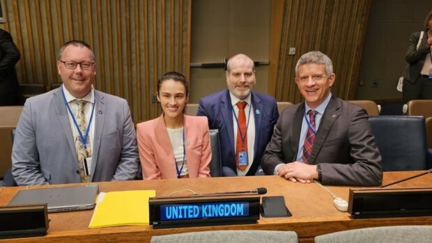 UK delegation sitting at a desk smiling to camera